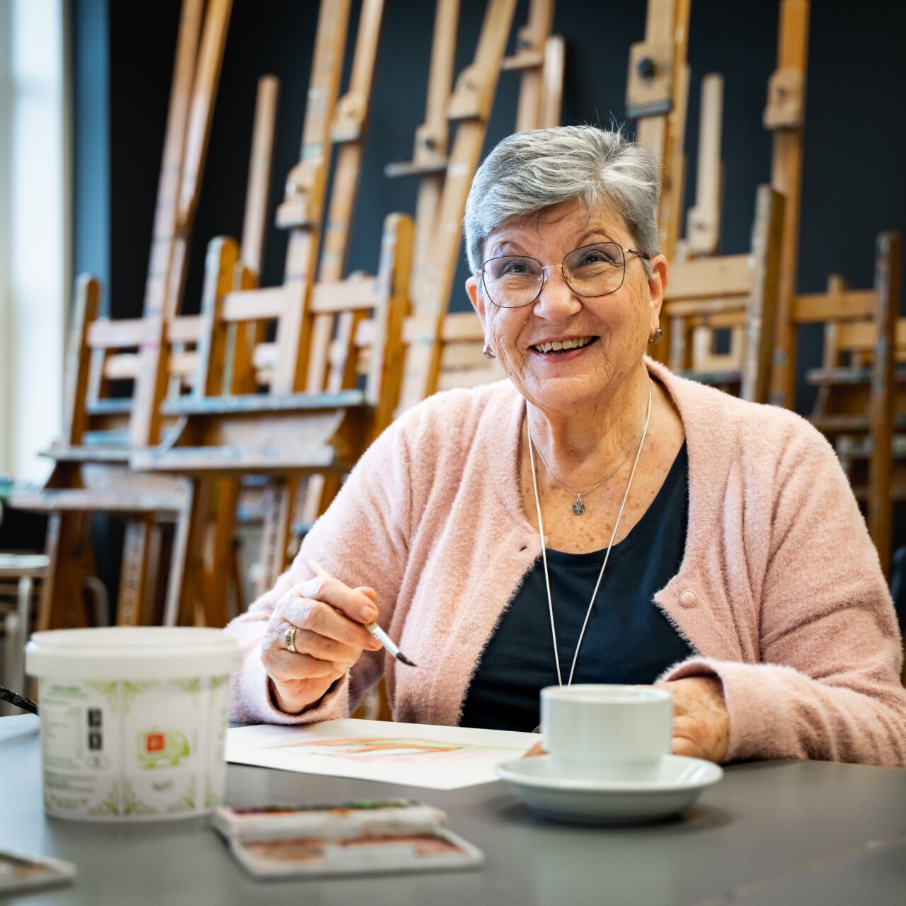 Een oudere mevrouw met beginnende dementie volgt een beeldende les.