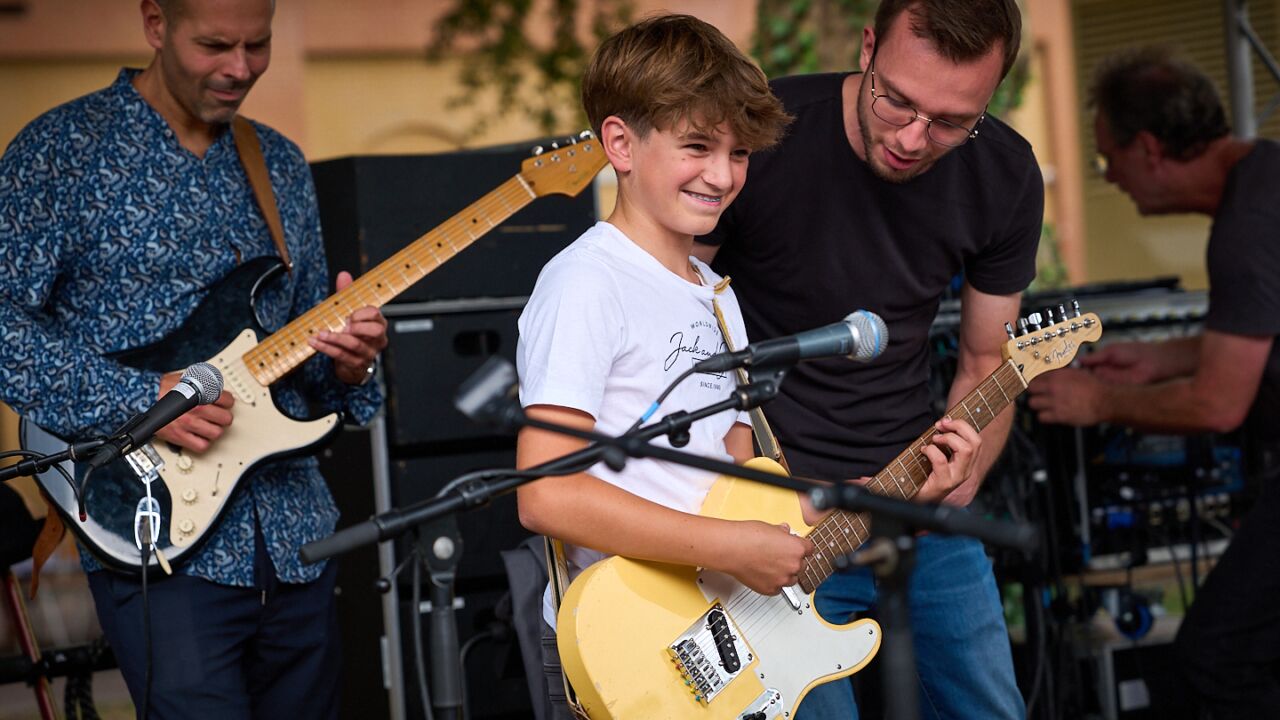 Twee docenten maken muziek met een leerling