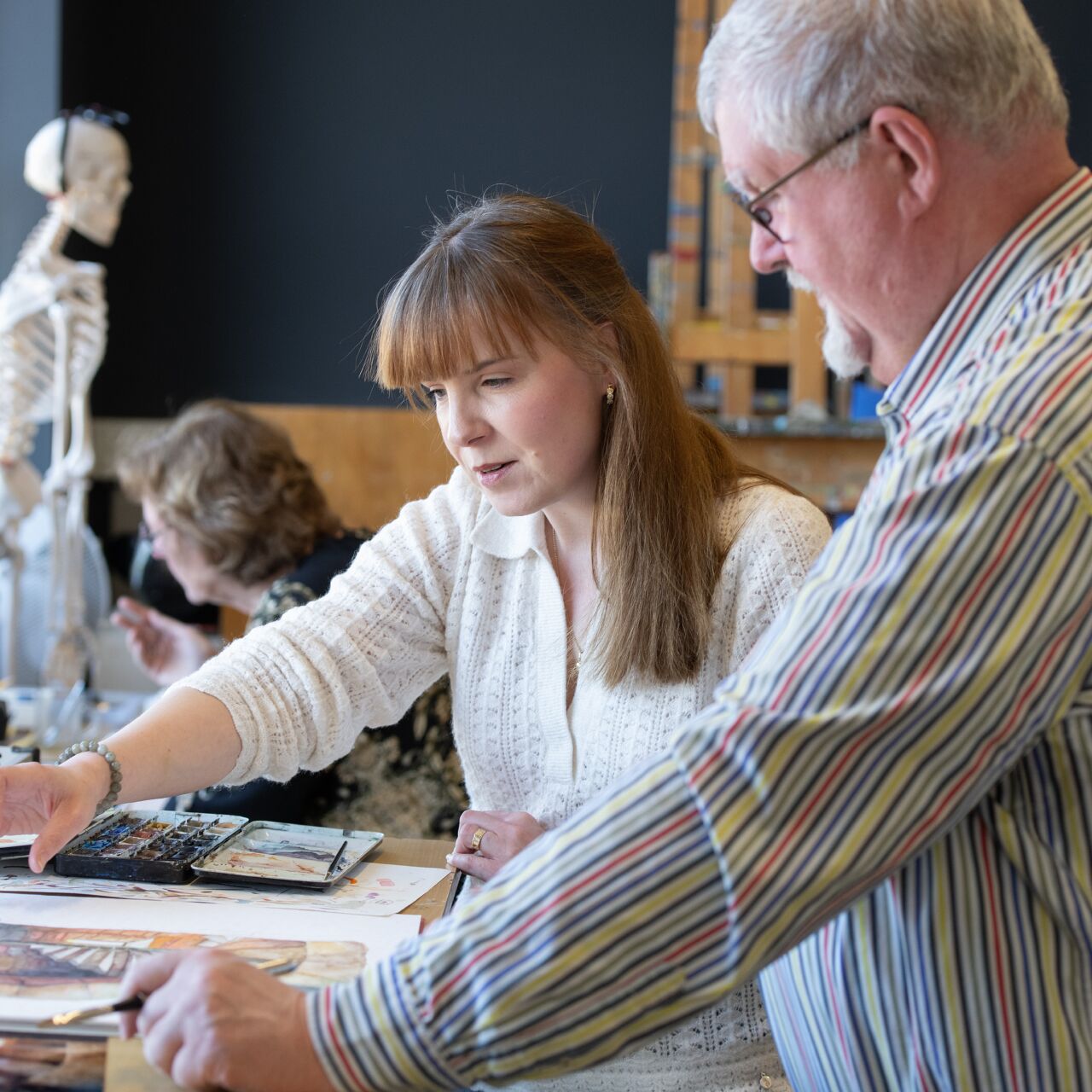 Docent geeft uitleg aan leerling tijdens les aquarel