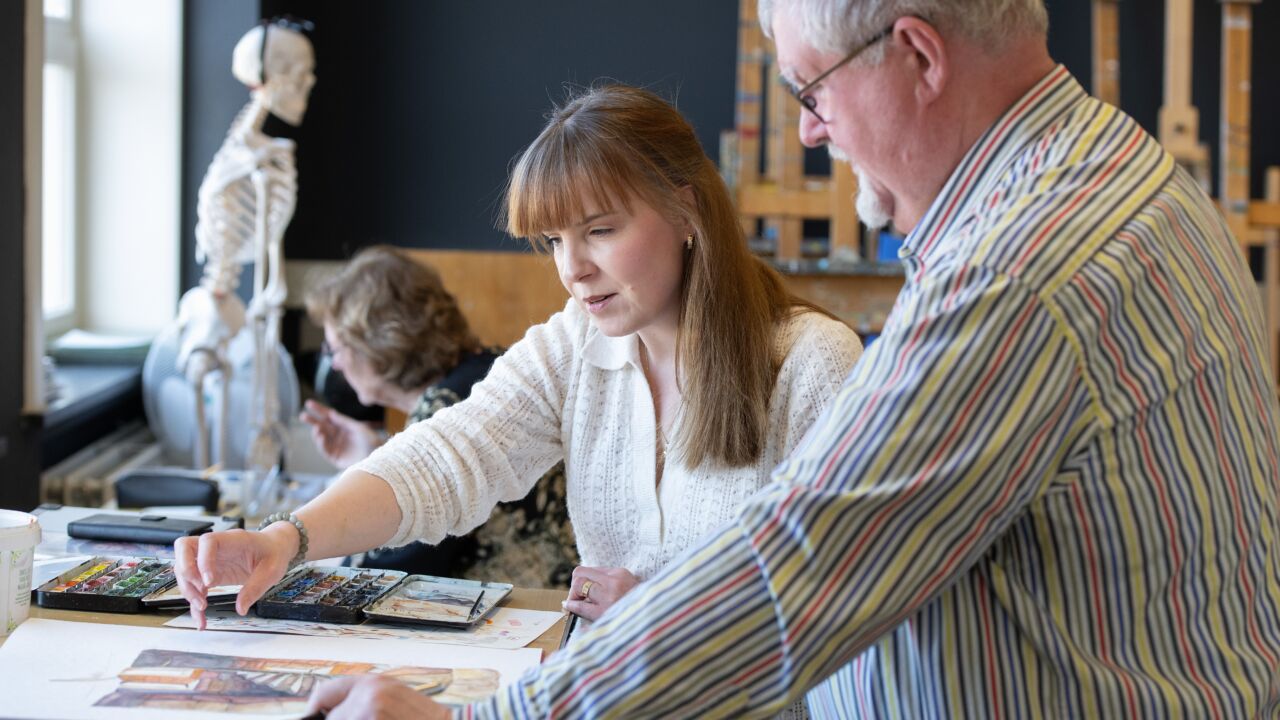Docent geeft uitleg aan leerling tijdens les aquarel