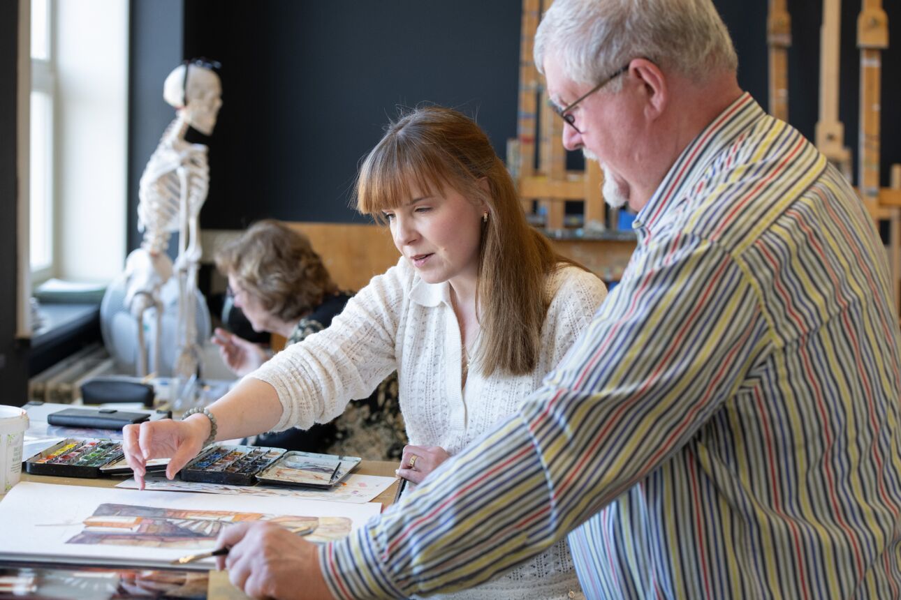 Docent geeft uitleg aan leerling tijdens les aquarel
