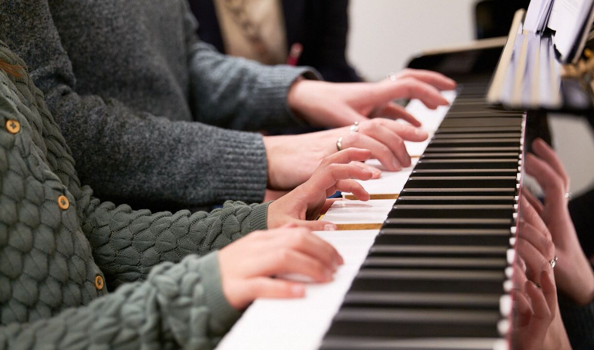 Een ouder en een kind krijgen samen pianoles
