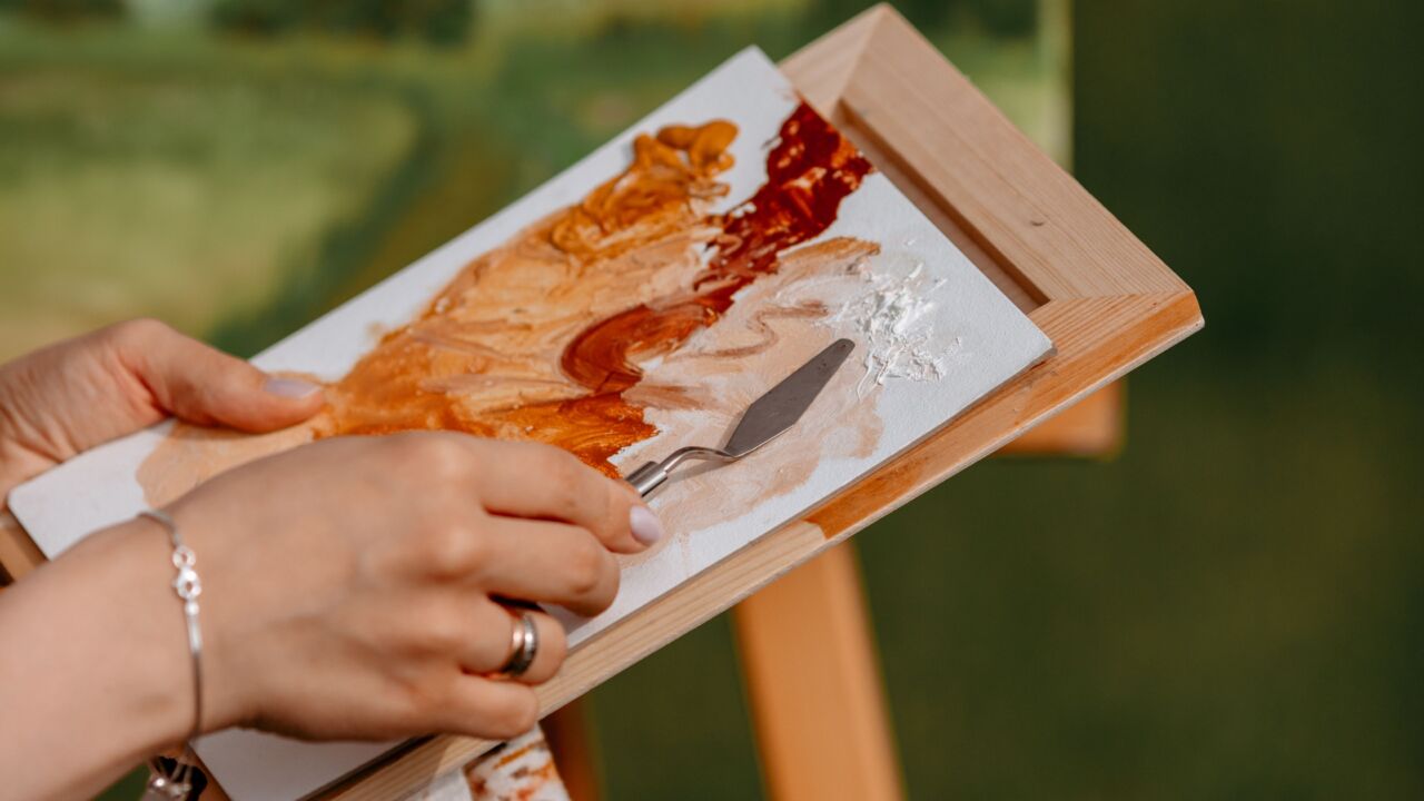 Cursiste is bezig met een landschapschilderij in de buitenlucht