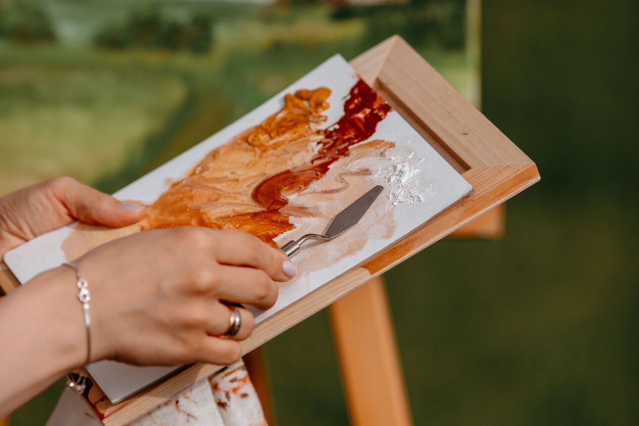 Cursiste is bezig met een landschapschilderij in de buitenlucht